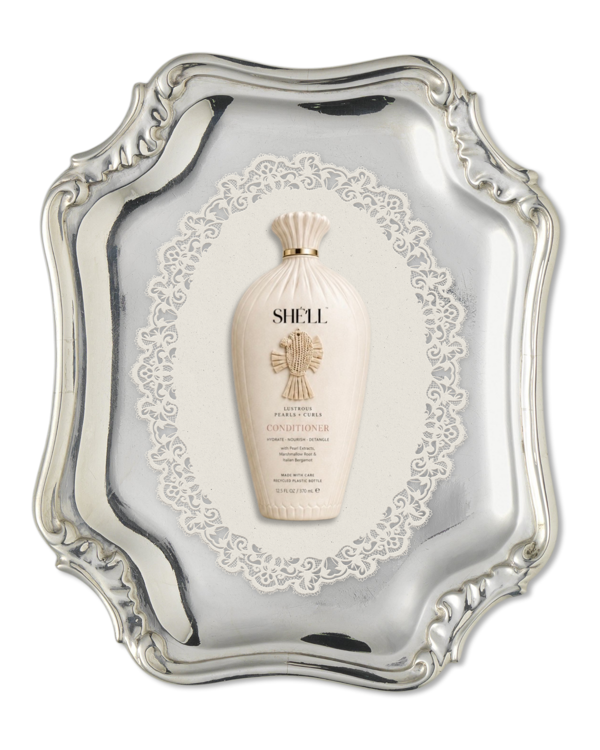 A bottle of Shell Radiance Conditioner centered on an ornate silver tray with a decorative white lace-like insert behind it.